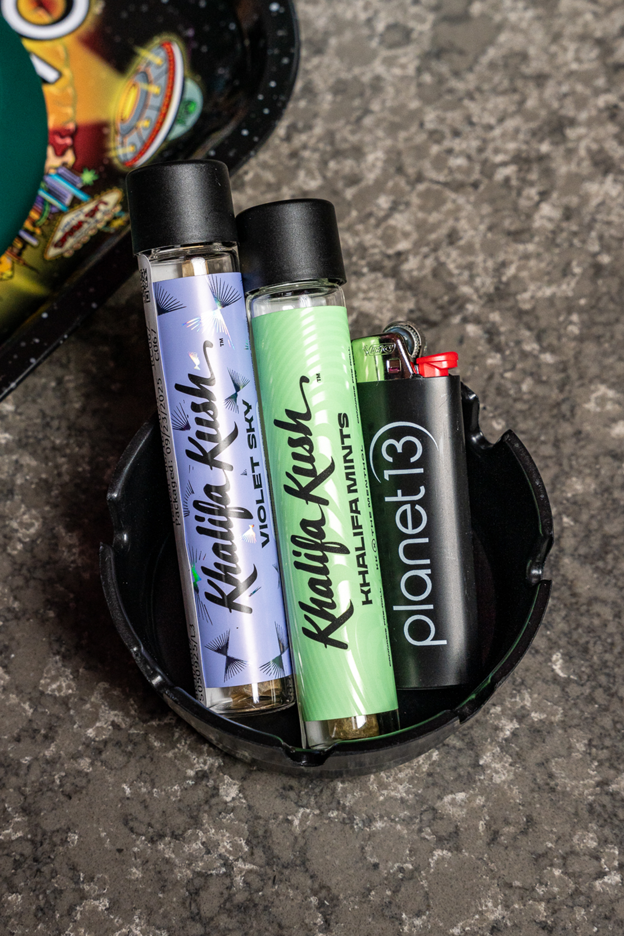 two khalifa kush pre roll tubes and a planet 13 lighter in a planet 13 ash tray